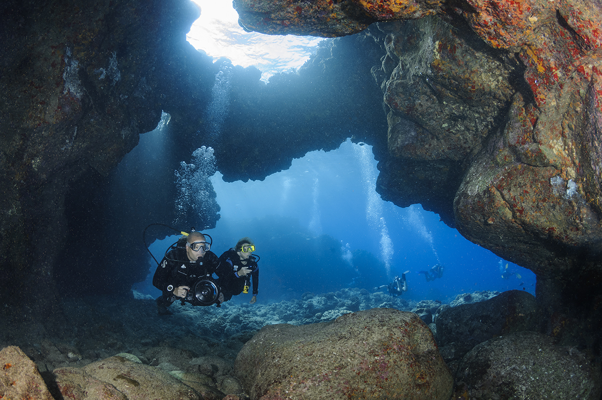 Two divers exploring a lava tube at a site called Aquarium off the Kona Coast of Hawaii's Big Island