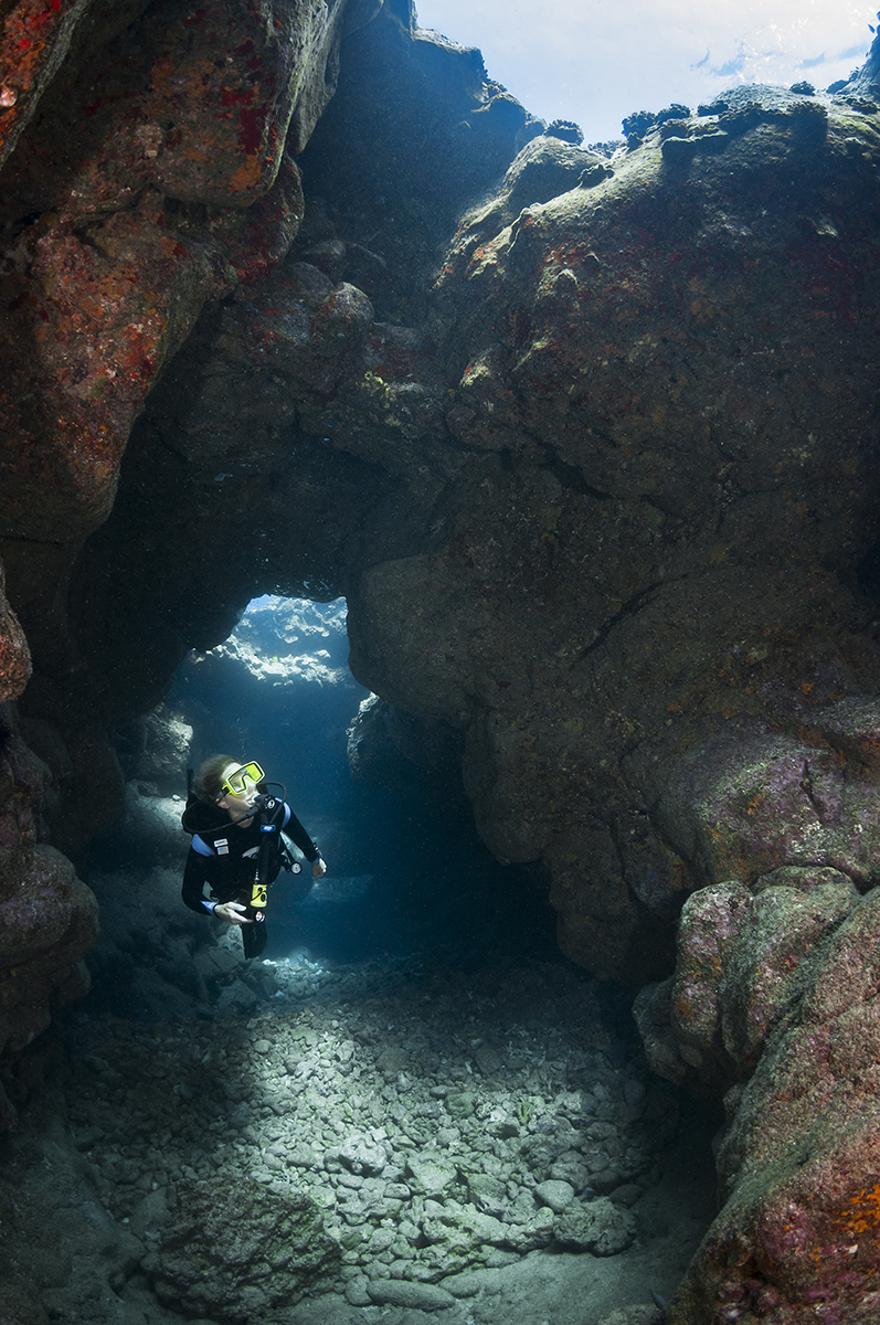 Diver exploring a lava tube at a site called Aquarium off the Kona Coast of Hawaii's Big Island